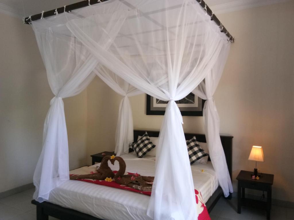 a bedroom with a canopy bed with white curtains at Puri Batu Inn in Pemuteran