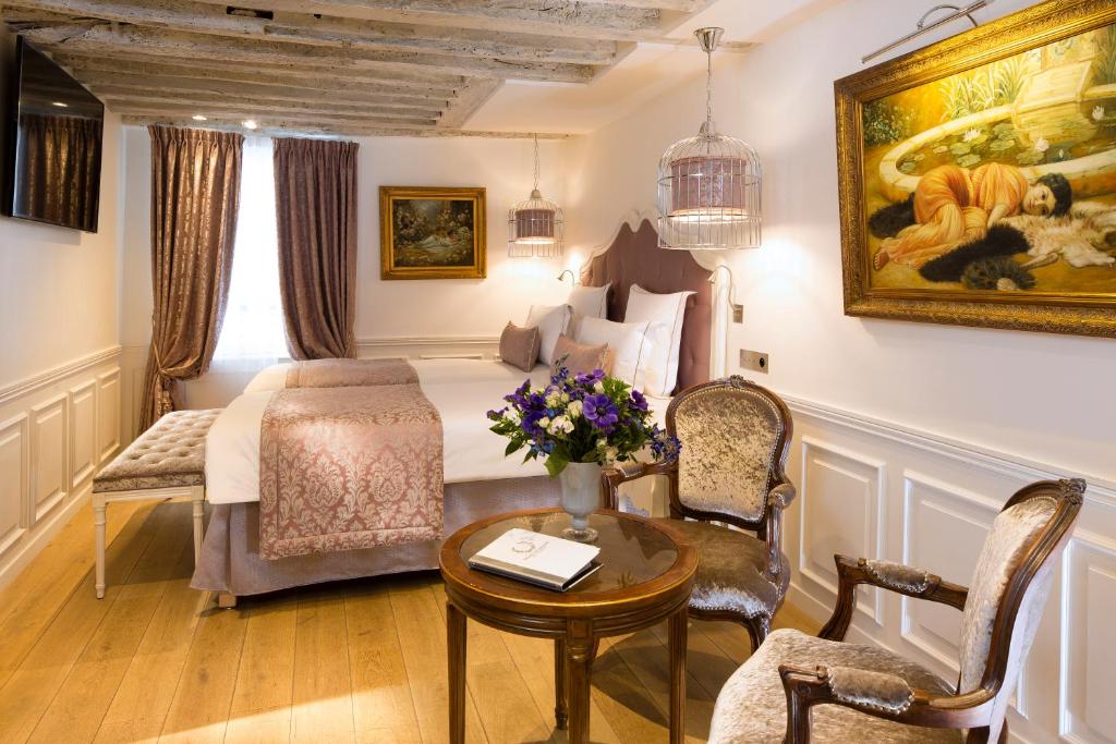 パリにあるアカデミー オテル サン ジェルマンのベッドと花のテーブルが備わるホテルルームです。