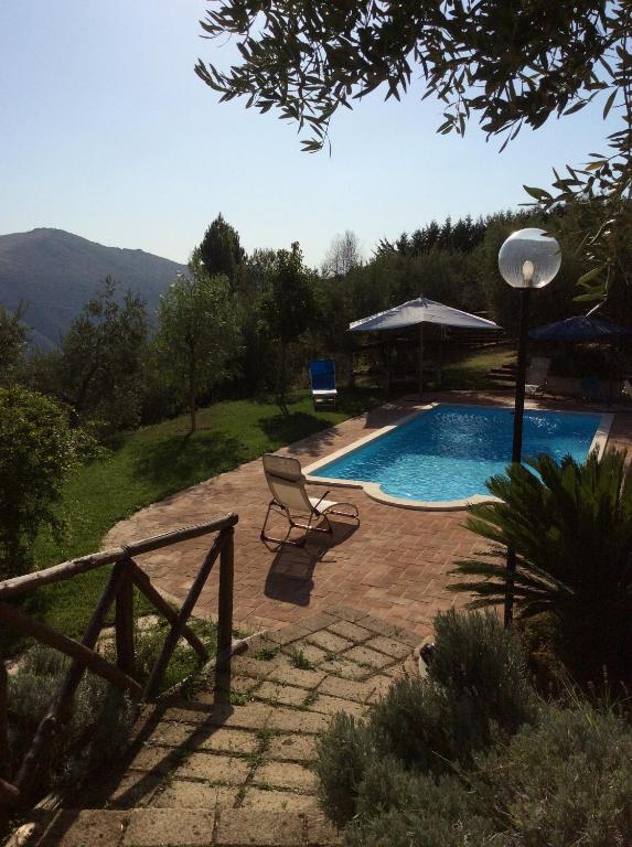 a swimming pool with a chair and an umbrella at Villa Panoramica con piscina in Castelnuovo di Farfa