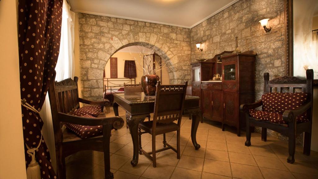 a dining room with a table and chairs and a stone wall at Amfitrion in Gythio