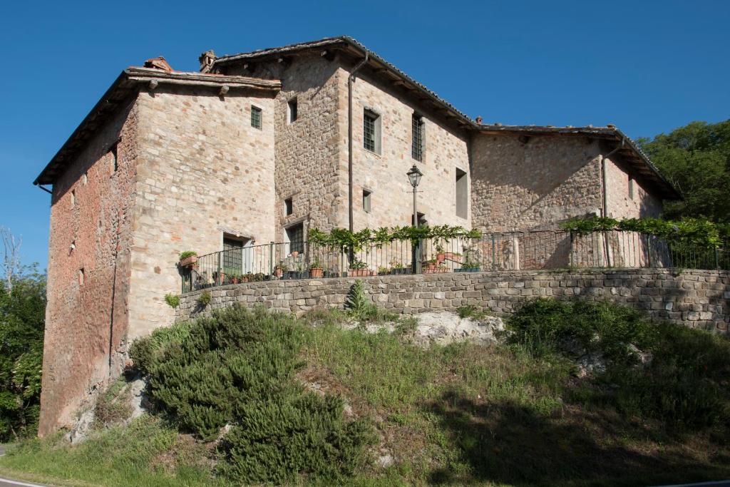 une vieille maison en pierre sur une colline avec une clôture dans l'établissement Tenuta Folesano Wine Estate 13th century, à Marzabotto