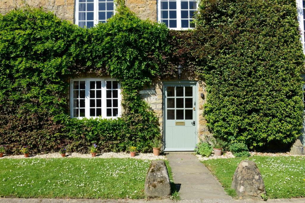 a stone house with a green door and ivy at Laverstock Cottage in Bridport