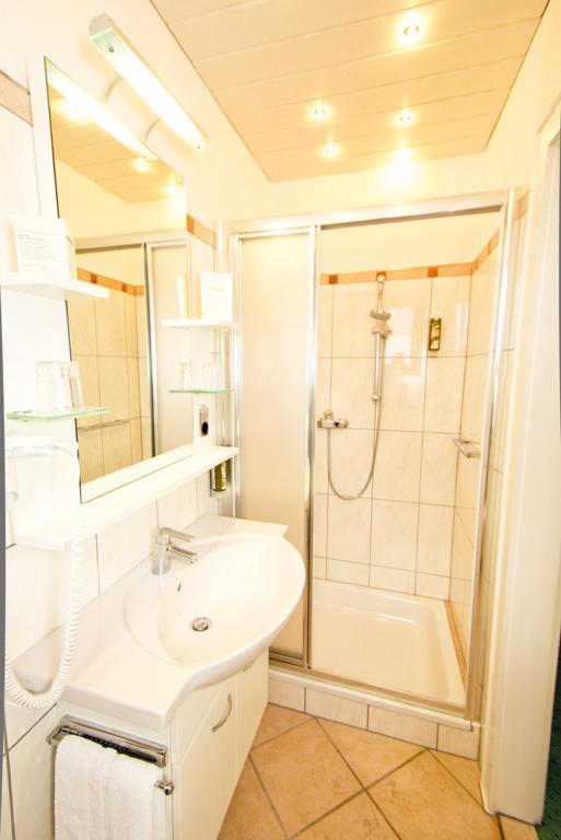 a white bathroom with a shower and a sink at Hotel Seewinkel in Fuschl am See