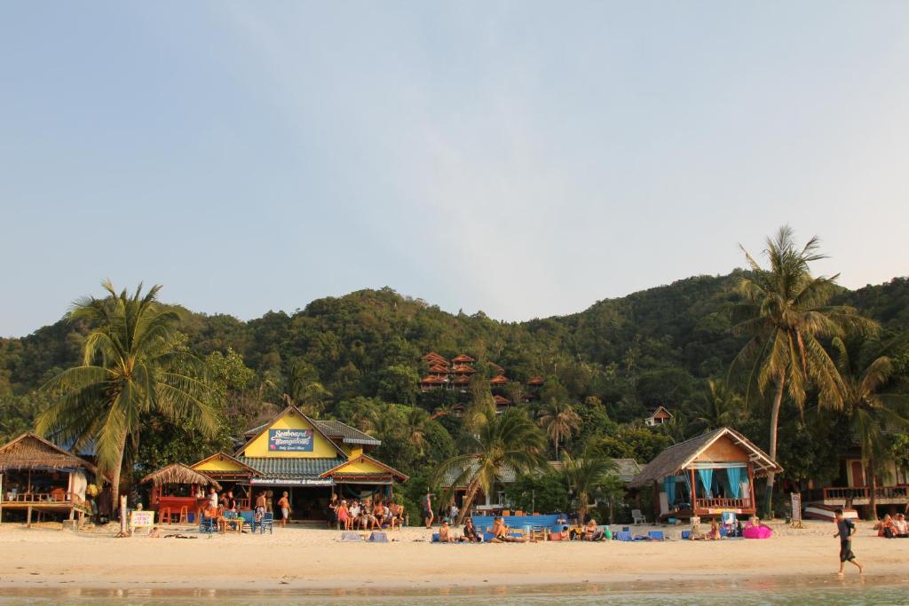 eine Gruppe von Menschen am Strand mit einem Berg in der Unterkunft Seaboard Bungalow in Haad Yao