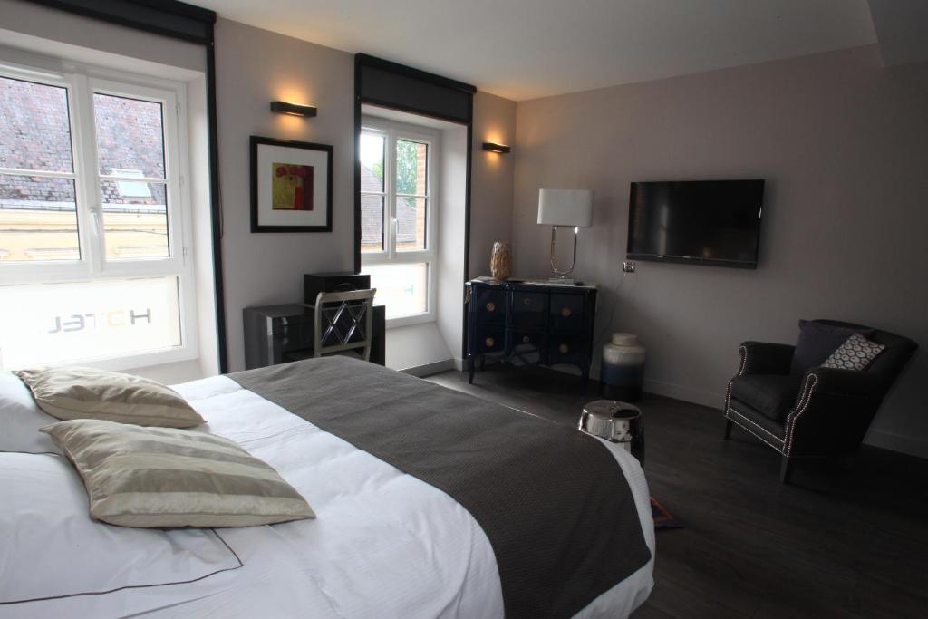 - une chambre avec un lit, une télévision et une chaise dans l'établissement LOGIS Hotel-Restaurant Le Relais d'Aligre, à Châteauneuf-en-Thymerais