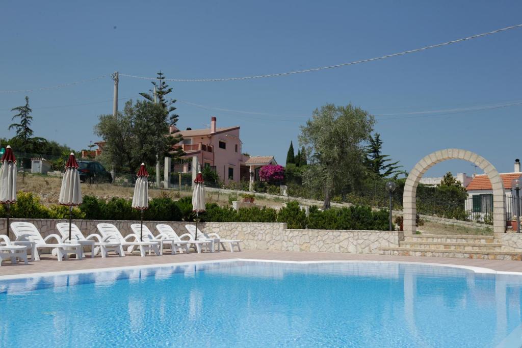 een groot zwembad met stoelen en parasols bij Villa Hibiscus in Vieste