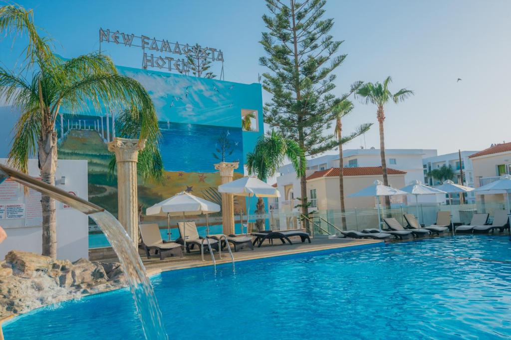a swimming pool with a fountain in front of a building at New Famagusta Hotel & Suites in Ayia Napa