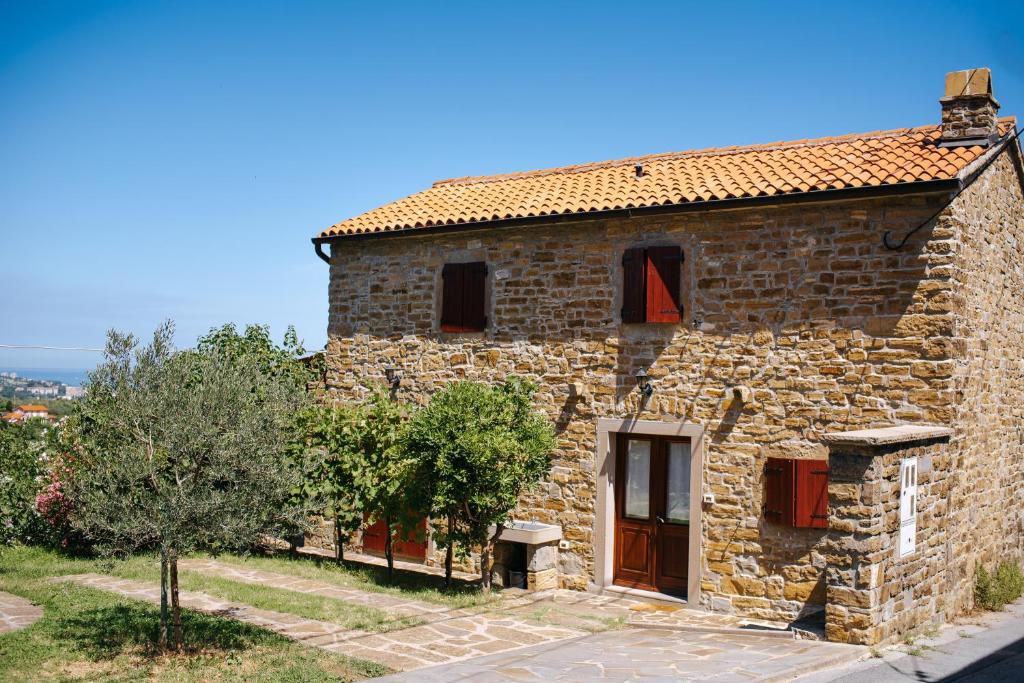 ein altes Steinhaus mit einer roten Tür und Bäumen in der Unterkunft Holiday home Manžan in Koper