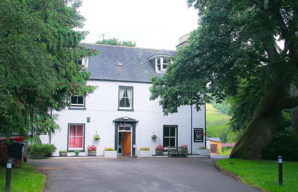 a white house with a red brick building at Benleva Hotel in Drumnadrochit