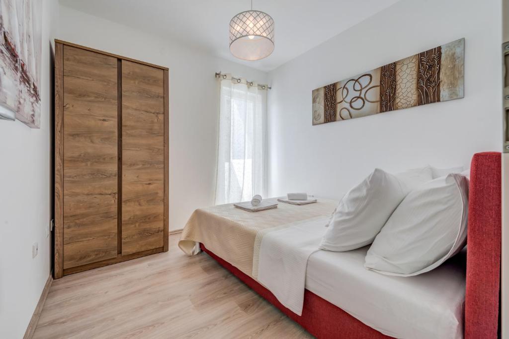 a white bedroom with a bed and a window at Chris's condo in Split
