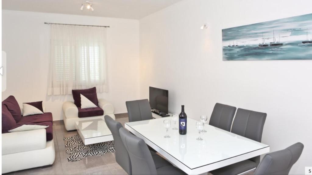 uma sala de estar com uma mesa branca e cadeiras em Apartment Barišić em Kaštela