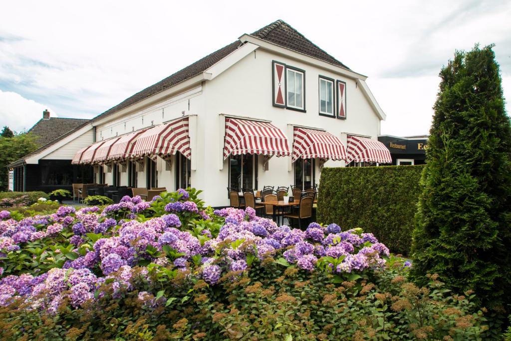 Un bâtiment blanc avec un bouquet de fleurs violettes dans l'établissement Hotel Restaurant Eeserhof, à Ees