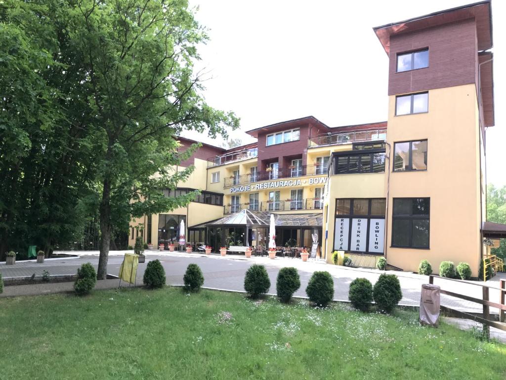 ein Gebäude an einer Straße mit Bäumen und Büschen in der Unterkunft Okulski Grand Rozewie Pokoje i Apartamenty in Jastrzębia Góra