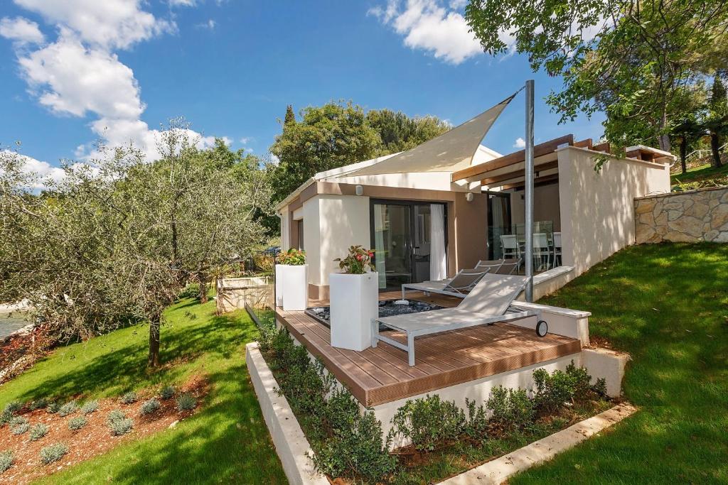 ein kleines Haus mit einer Terrasse und einer Liegewiese in der Unterkunft Villas Bellevue Plava Laguna in Poreč