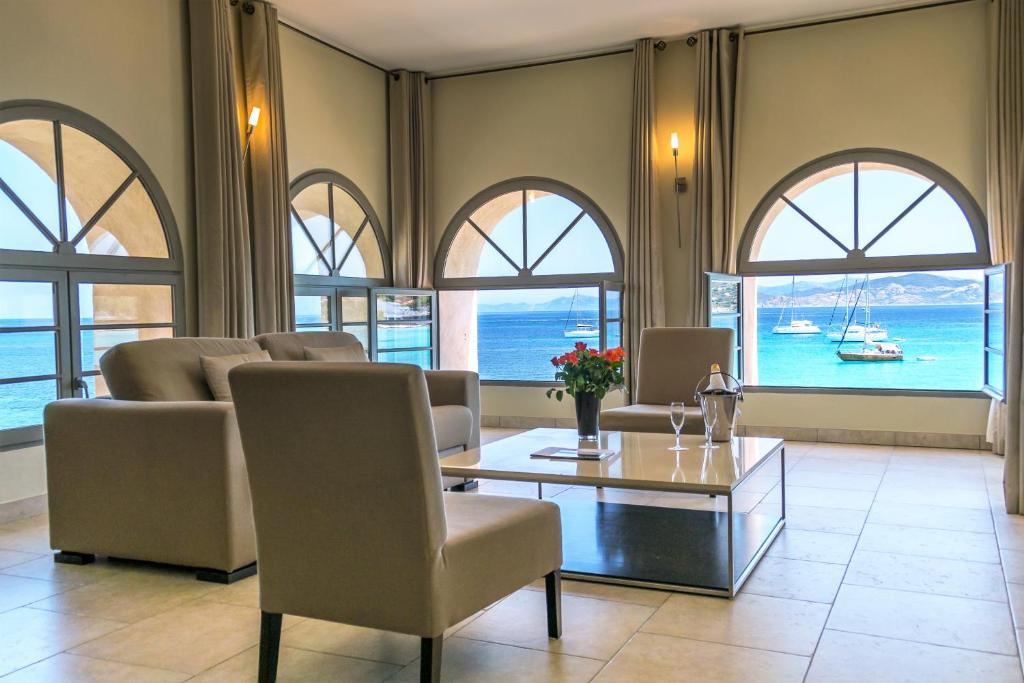 sala de estar con mesa, sillas y ventanas en Perla Rossa, en LʼÎle-Rousse