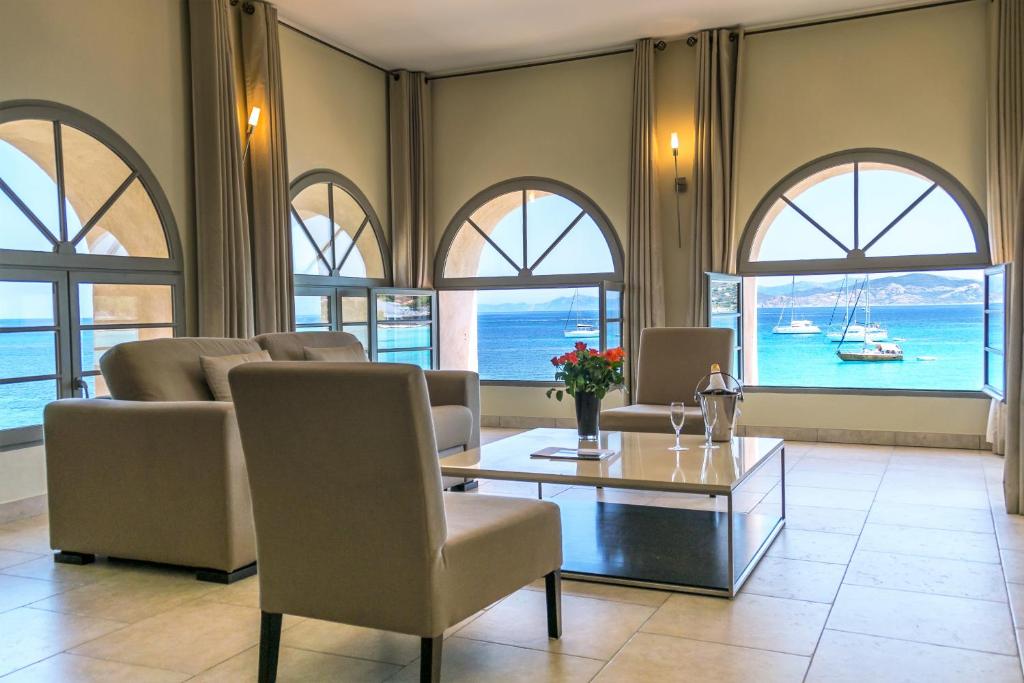 a living room with a table and chairs and windows at Perla Rossa in LʼÎle-Rousse