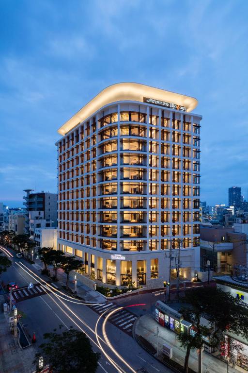 a large building with a lit up top on a city street at JR Kyushu Hotel Blossom Naha in Naha