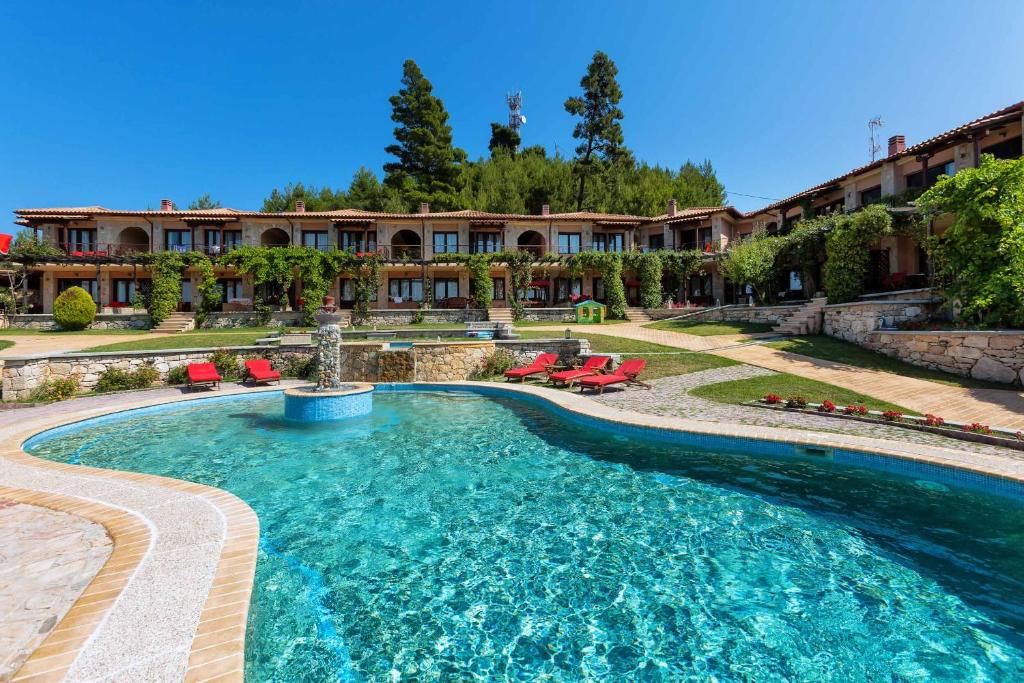 a swimming pool in a yard with chairs and a building at Akritas Ef Zin Villas & Suites in Paliouri