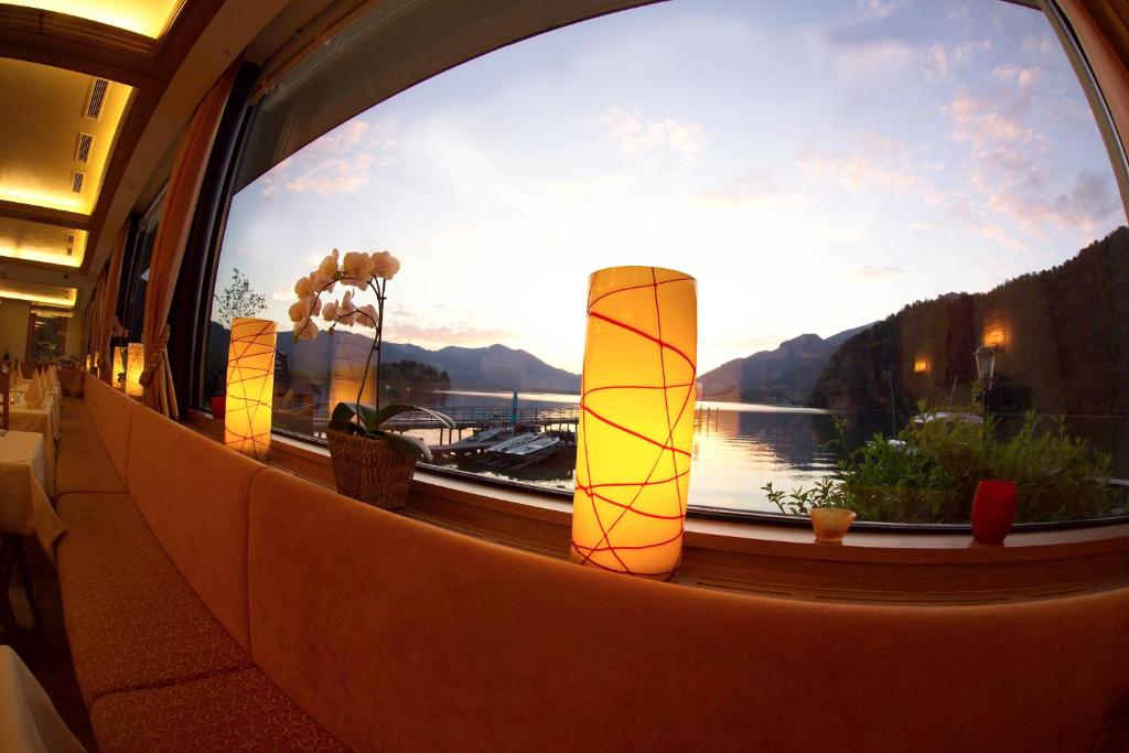 a window with a view of a lake and mountains at Seehotel Lilly in Strobl