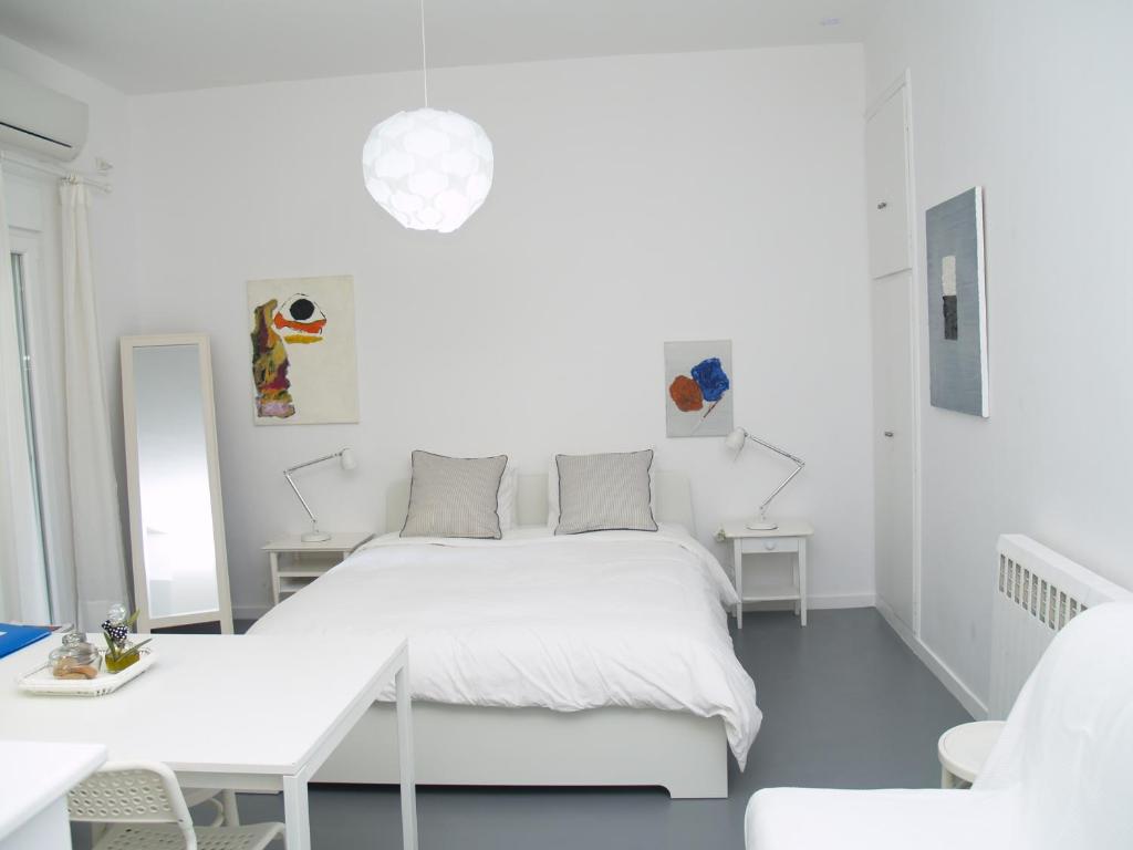 a white bedroom with a white bed and a table at Newly Renovated Apt in Kolonaki in Athens