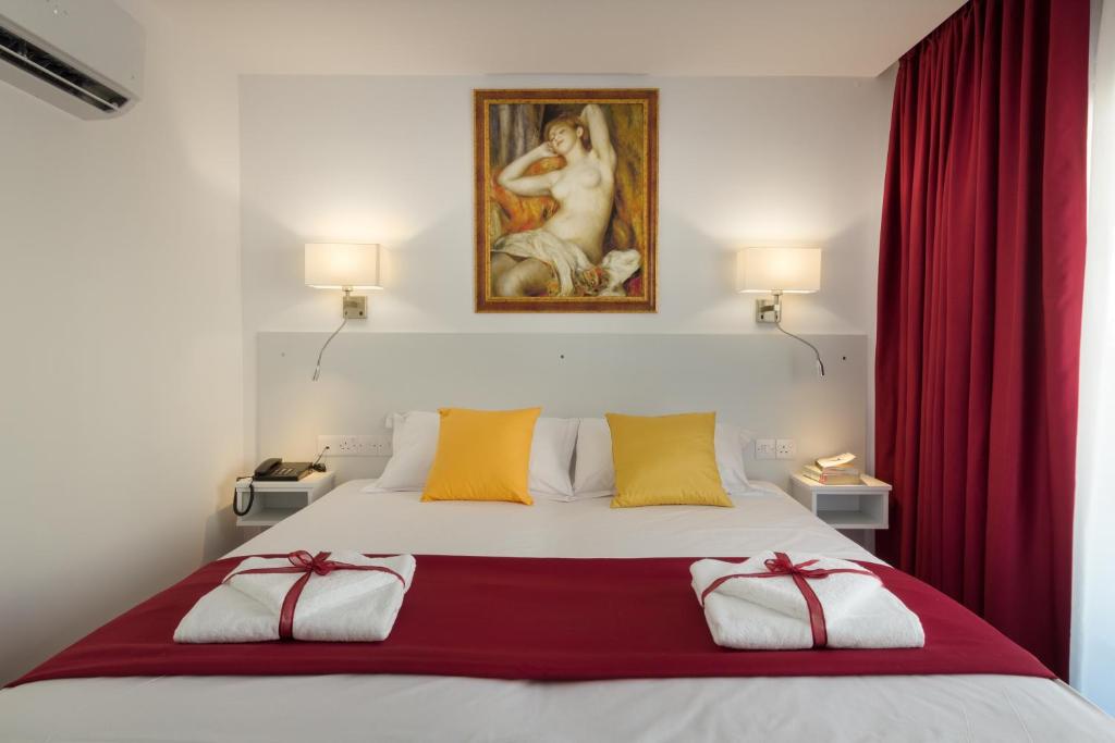 a bedroom with a bed with red curtains and a painting at Art & Wine Studios and Apts in Larnaca