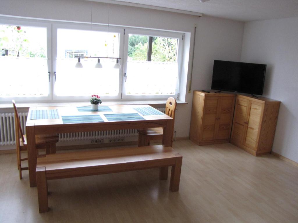 un soggiorno con tavolo in legno e TV di Ferienwohnung Dettenhausen a Dettenhausen