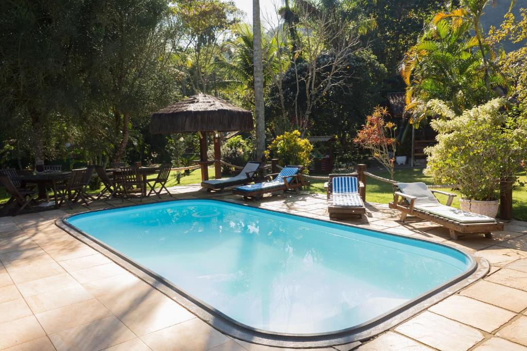 una grande piscina con sedie e gazebo di Pousada Recanto dos Lima a Praia do Bananal