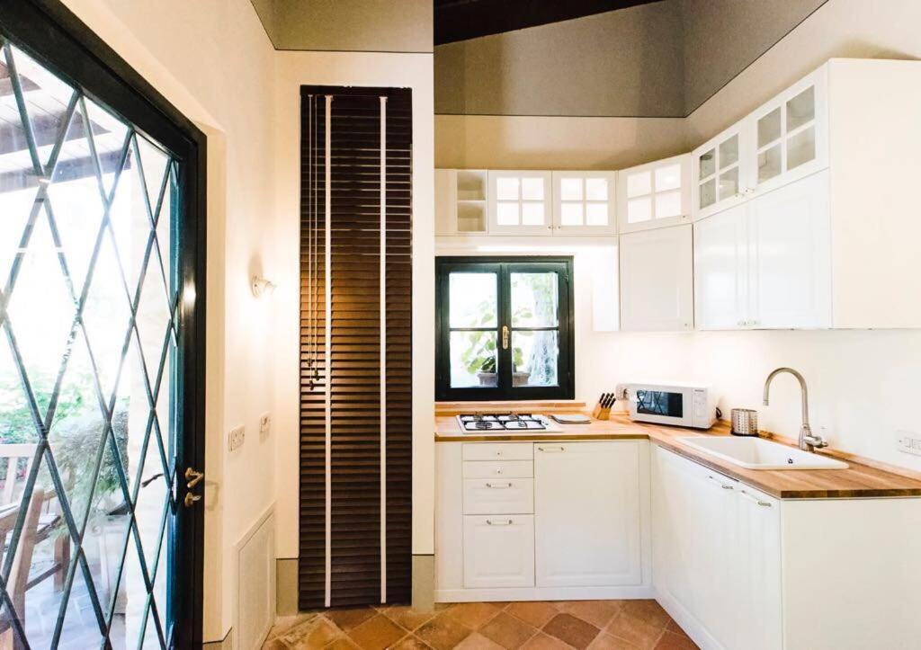 a kitchen with white cabinets and a large window at Dimora Borgogni: Country House in Perugia