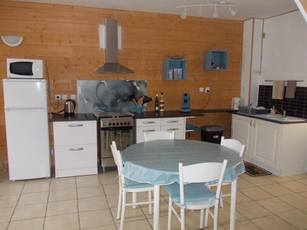 a kitchen with a table and chairs and a kitchen with a refrigerator at Epi-Centre in Préaux