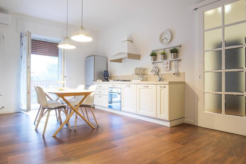 a kitchen with white cabinets and a table and chairs at Oikos in Matera