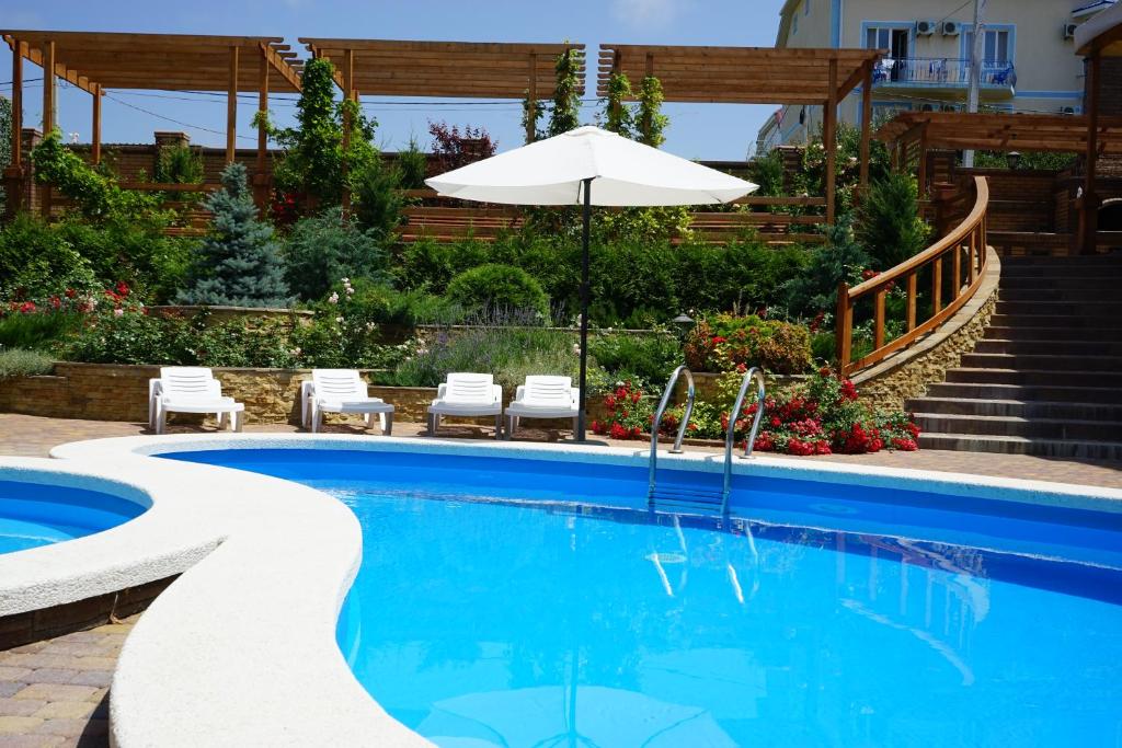 a swimming pool with an umbrella and chairs and stairs at Aristokrat Hotel in Nizhneye Dzhemete