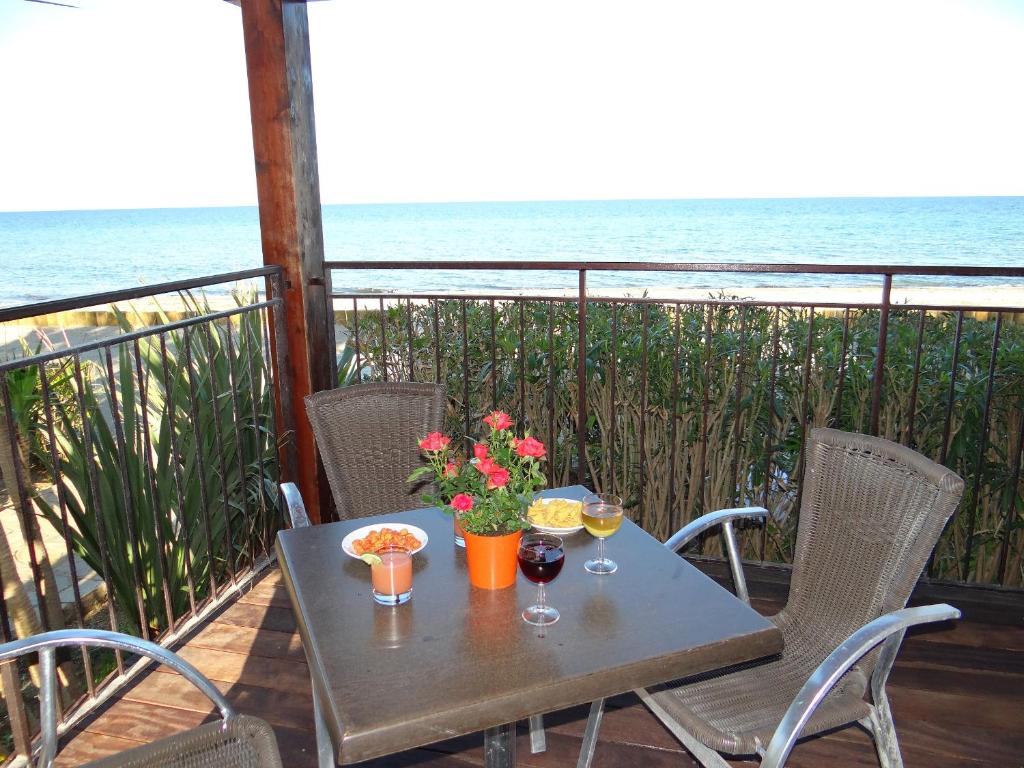 una mesa con 2 copas de vino y flores en el balcón en Vue sur mer et montagnes en Moriani Plage