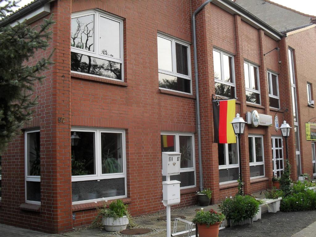 ein rotes Backsteingebäude mit Fenstern und Flaggen darauf in der Unterkunft Pension-Roexe in Stendal