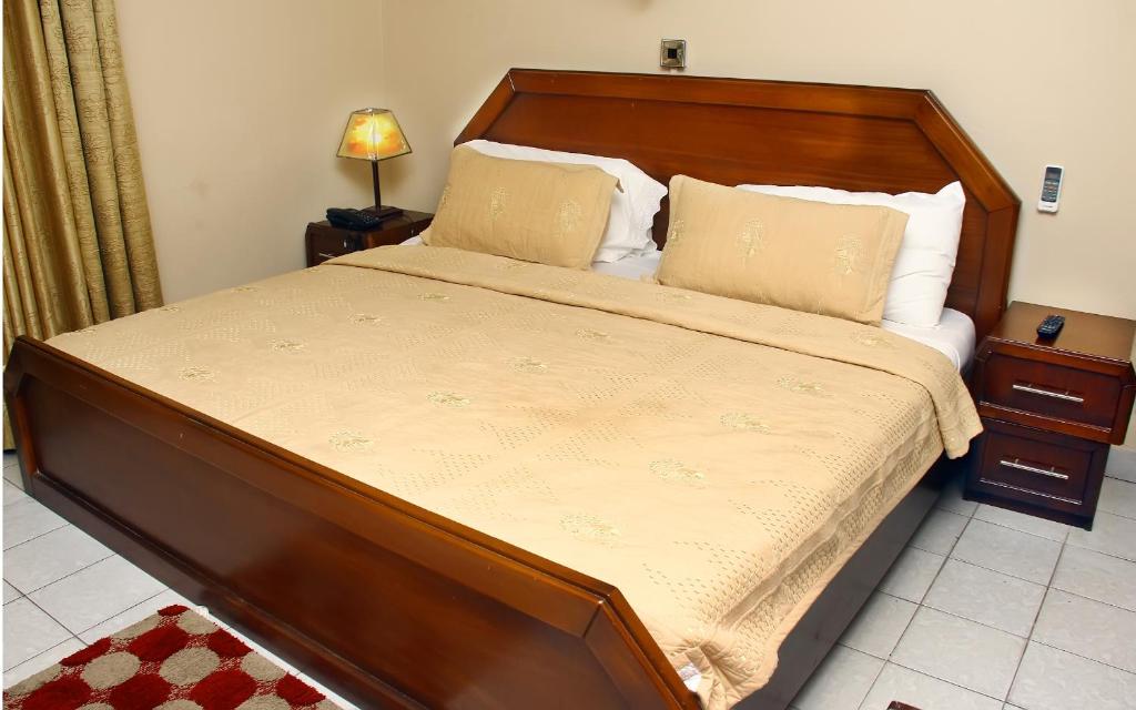 a large bed with a wooden headboard in a bedroom at Stadium Hotel in Kumasi