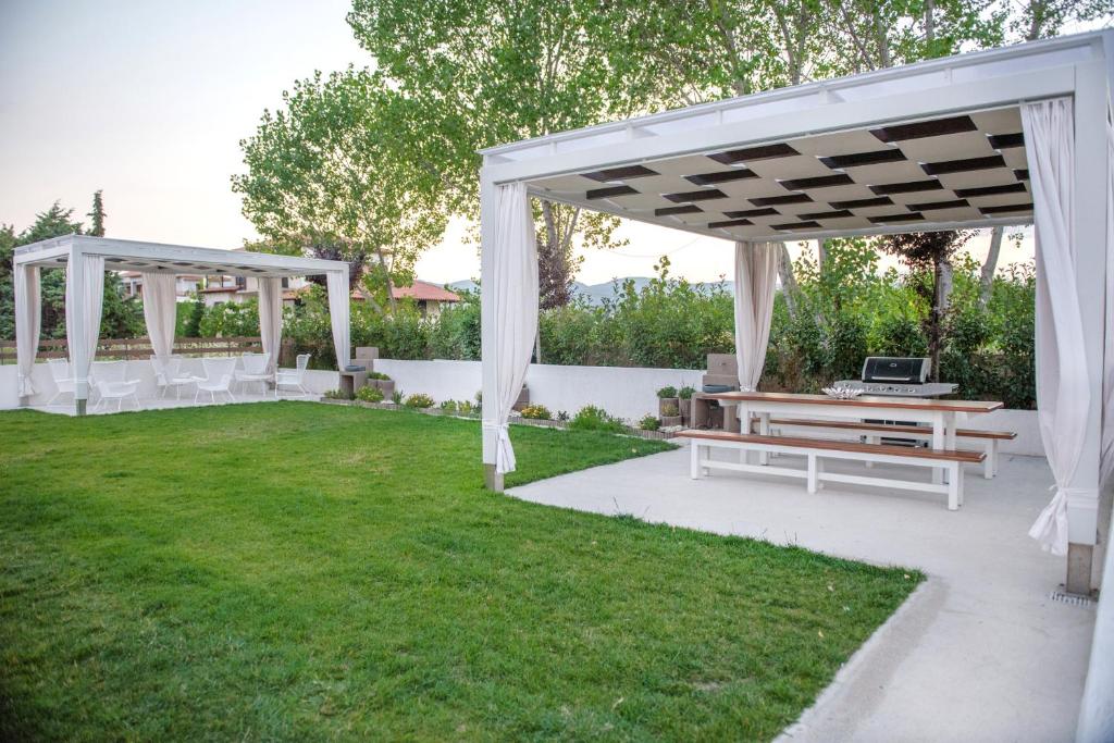 una pérgola blanca y bancos en un patio en Corali luxury villas, en Ierissos
