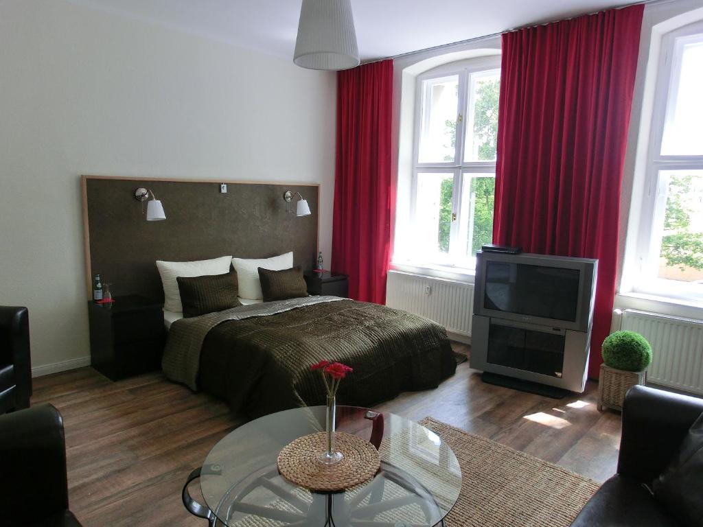 a bedroom with a bed with red curtains and a tv at Apartment KiezFlair in Potsdam