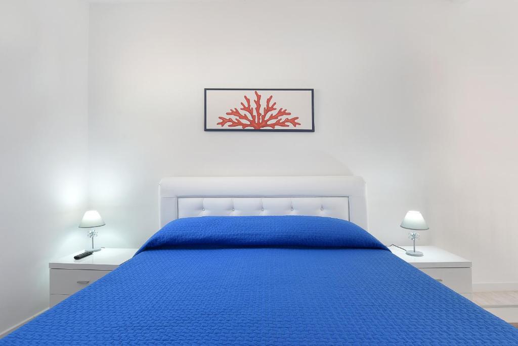 una camera bianca con un letto blu e due lampade di Marina Grande Inn a Sorrento
