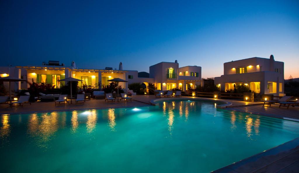 een groot zwembad 's nachts met gebouwen bij Naoussa Bay Villas in Naousa