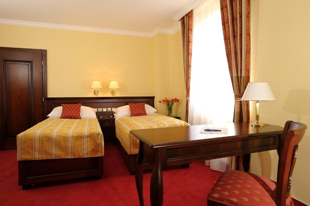 a hotel room with two beds and a table at Hotel U Krále in Jičín