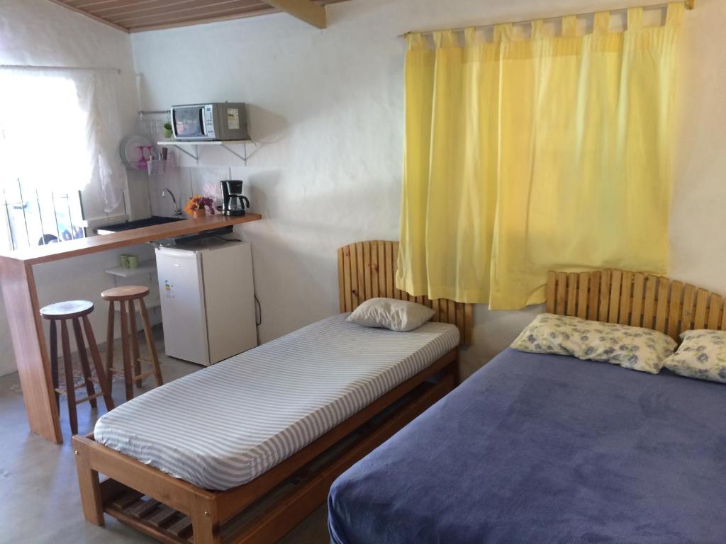 1 dormitorio con cama y cortina amarilla en Kitchenette Charmosa no Itagua, en Ubatuba