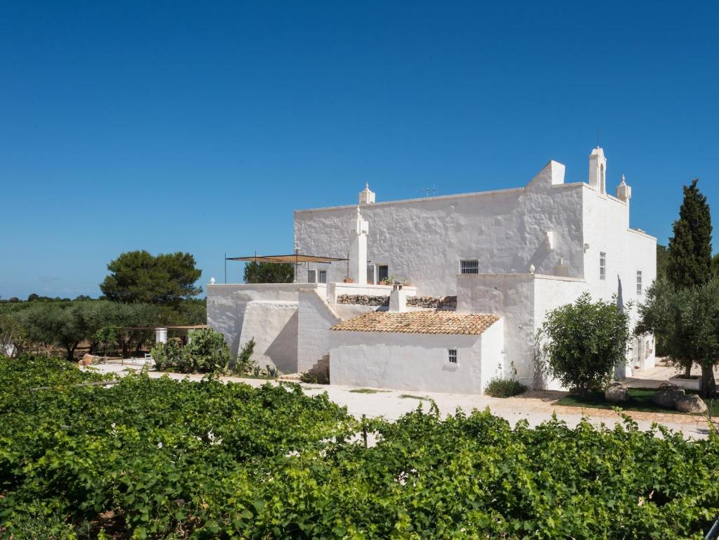 un bâtiment blanc avec des arbres devant dans l'établissement Masseria Le Cerase, à Conversano
