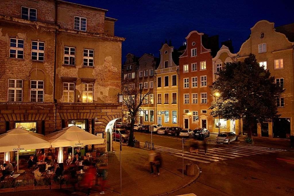 a group of people walking around a street at night at Pokoje na Pańskiej 9 in Gdańsk