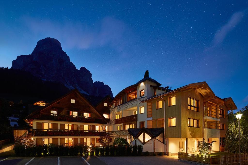 un grand bâtiment en face d'une montagne la nuit dans l'établissement Residence Mugun, à Corvara in Badia