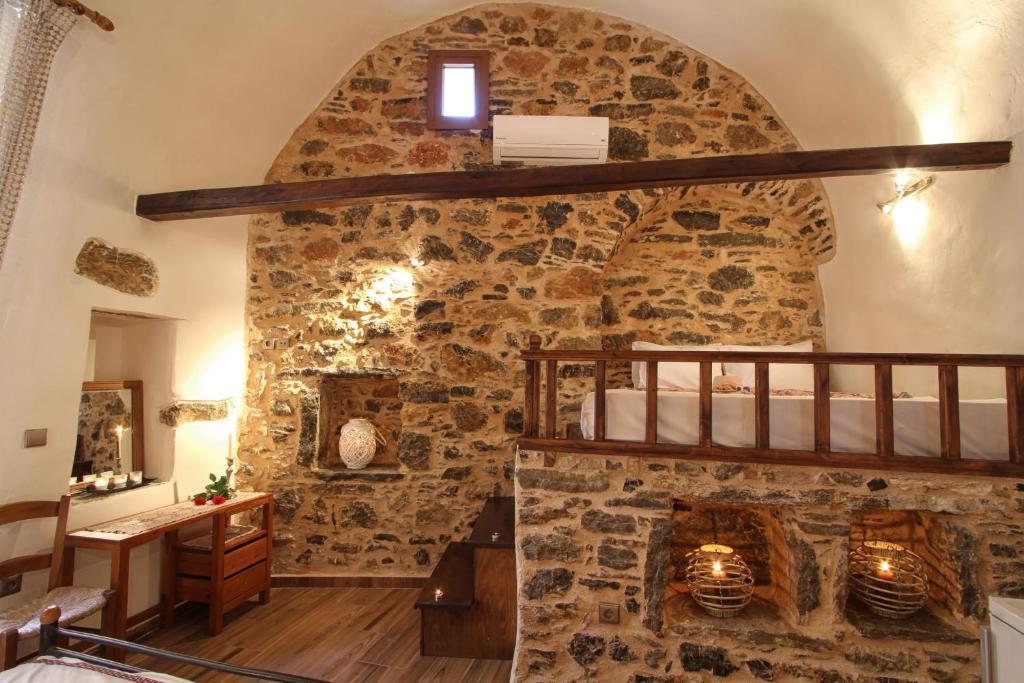 a room with a stone wall with a fireplace at Schinos Apartments in Mestá