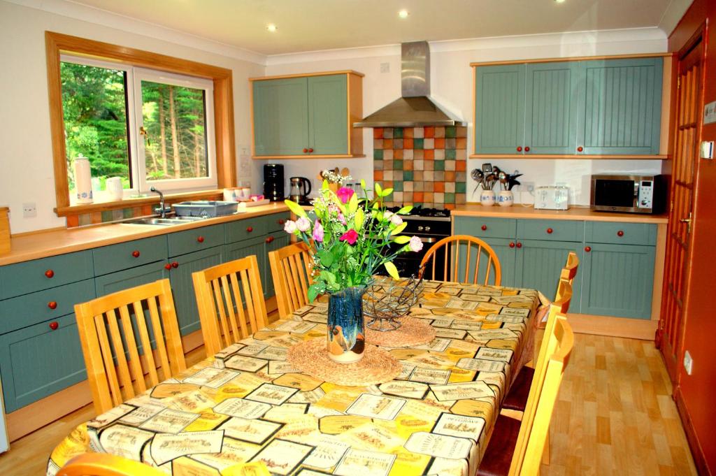een keuken met een tafel met een vaas met bloemen erop bij Torcroft Lodges in Drumnadrochit
