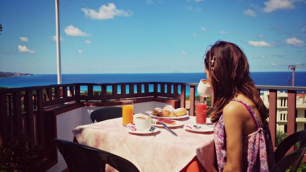 una mujer sentada en una mesa con una taza de café en San Carlo - Terrazzo sul Mare con Ristorante e Pizzeria, en Zambrone