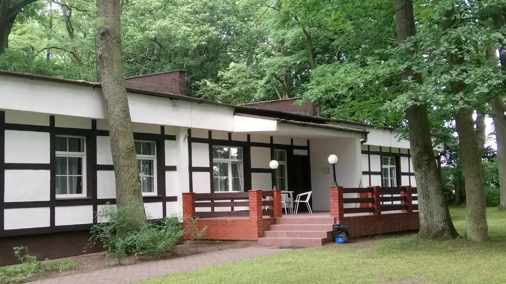 ein weißes und schwarzes Haus mit einer Veranda in der Unterkunft Hostel Dworek Osiecki KORAL in Osieki