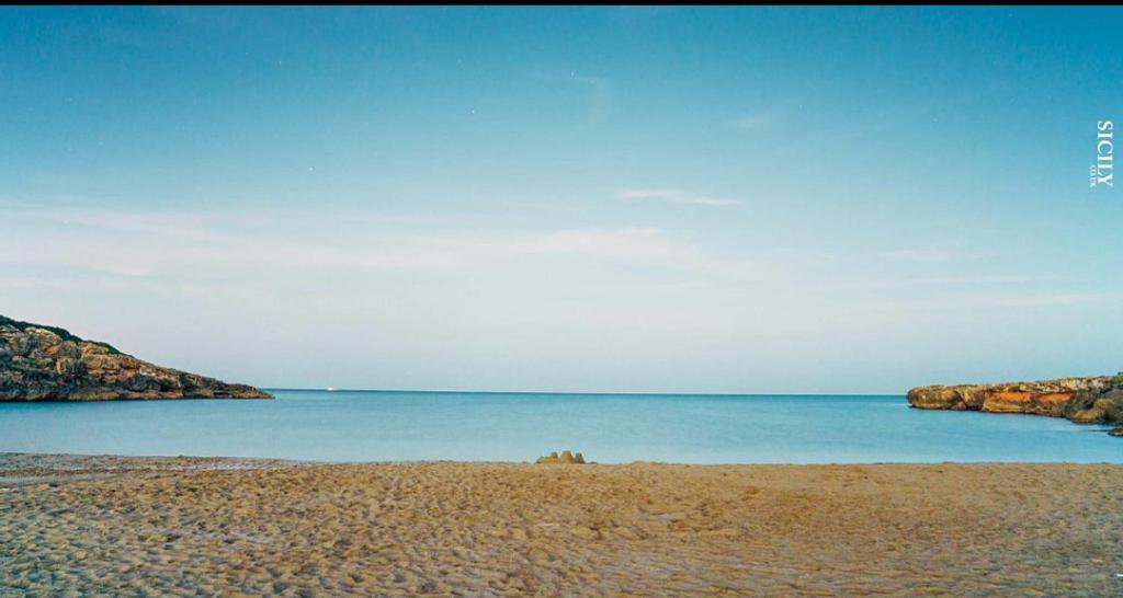 een zandstrand met rotsen in het water bij Tempo Di Vendicari in La Banca