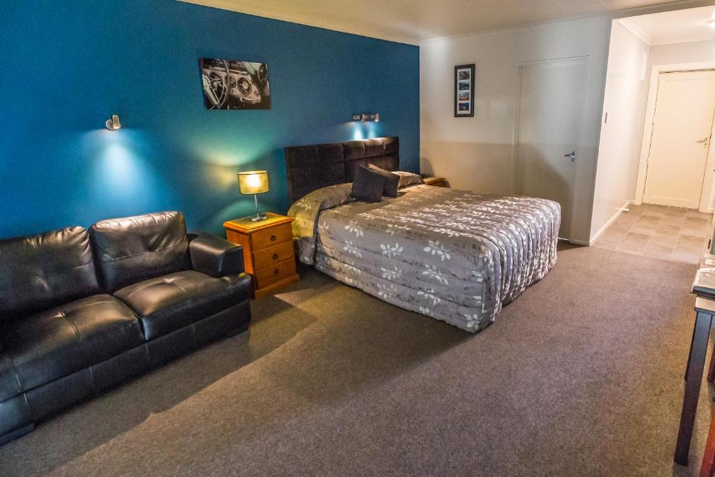 a bedroom with a bed and a leather couch at AAA Thames Court Motel in Oamaru