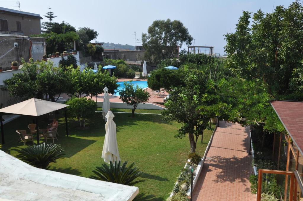 uma vista para um quintal com uma piscina e um guarda-sol em Hotel Savoia em Procida